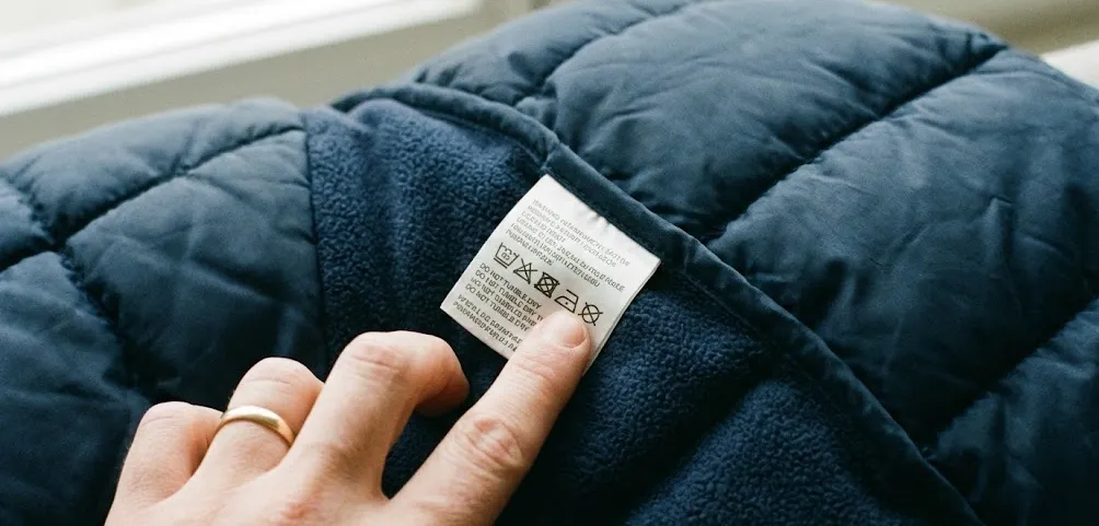 겨울 패딩 재킷과 세탁 라벨을 가리키는 손